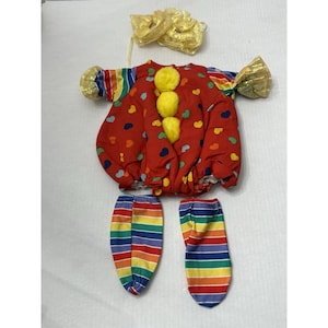 May include: A colorful clown costume set. The red top is decorated with hearts and yellow pom-poms. The sleeves and leg coverings feature rainbow stripes. A yellow bow and gold accents complete the outfit. Perfect for a costume party or Halloween.