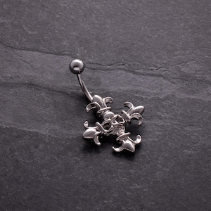 May include: A silver belly button ring with a fleur-de-lis cross design. The curved barbell has a small ball at the top and a decorative cross at the bottom. The cross features intricate details and a small gem.