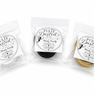 Puede incluir: Tres bolsas de pl&aacute;stico transparente que contienen bandas met&aacute;licas enrolladas en plata, negro y oro. Cada bolsa tiene una etiqueta cuadrada blanca con el texto negro You've Been Pixie Dusted by the Meeks Family, Stateroom 7106, A Little Magic Just For You.