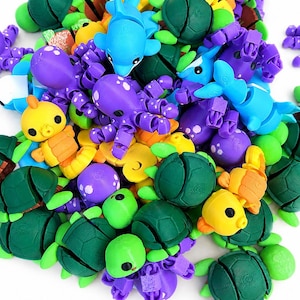 May include: A collection of small, articulated plastic animal figures including green turtles, purple octopuses, blue dolphins, and yellow seahorses. Each figure features a segmented design with visible 3D printed textures and smooth, rounded surfaces.