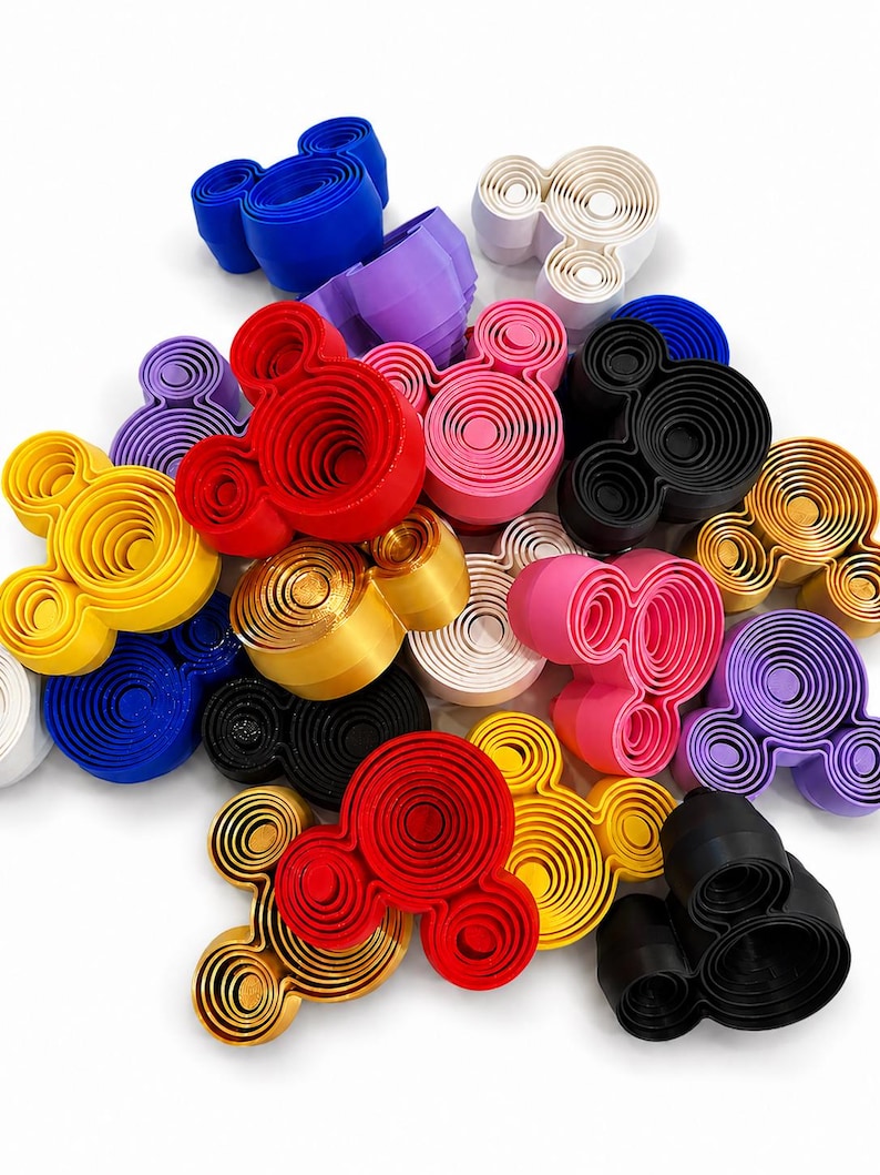 Puede incluir: Una colecci&oacute;n de cortadores de galletas tridimensionales con forma de rat&oacute;n en varios colores s&oacute;lidos, incluyendo rojo, azul, amarillo, negro, blanco, rosa, morado y dorado. Cada cortador presenta un dise&ntilde;o de c&iacute;rculos conc&eacute;ntricos.