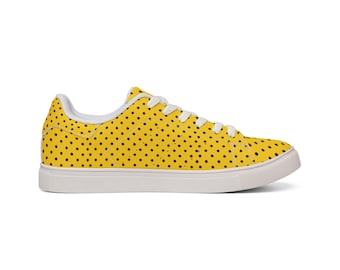 May include: A low-top sneaker featuring a vibrant yellow upper covered in a repeating pattern of small black polka dots. The shoe includes white laces, a white interior lining, and a thick white rubber sole with a textured toe and heel area.