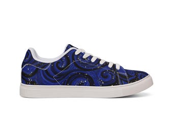 Op de afbeelding: Lage sneakers met een blauw en zwart wervelend patroon, geaccentueerd met kleine gouden stippen. De schoen heeft een witte zool en witte veters.