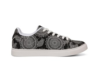 May include: A low-top sneaker featuring a black upper with a white intricate mandala pattern. The shoe includes white laces, a white interior lining, and a thick white rubber sole. The design covers the entire exterior surface of the footwear.
