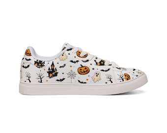Puede incluir: Una zapatilla baja blanca con un patrón repetitivo de temática de Halloween. El diseño incluye calabazas naranjas, siluetas negras de casas encantadas, murciélagos, árboles sin hojas, telarañas y pequeños fantasmas blancos sobre fondo.