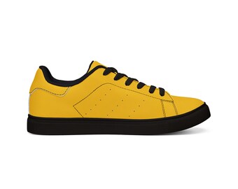 May include: A low-top sneaker featuring a vibrant yellow upper with black laces, a black interior lining, and a solid black rubber sole. The side panel displays a subtle perforated pattern, and the design includes black stitching details.