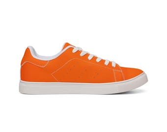 May include: A low-top sneaker in a vibrant orange color featuring a solid orange upper, white laces, a white interior lining, and a thick white rubber sole. The side panel displays a subtle stitched pattern with small perforated ventilation holes.