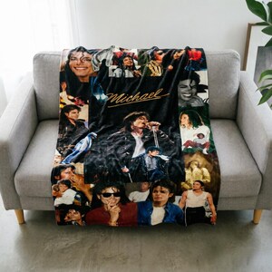 May include: A black and white fleece throw blanket featuring a collage of various photographs of Michael Jackson in different outfits and poses, with the name Michael written in a gold cursive script across the center of the fabric design.