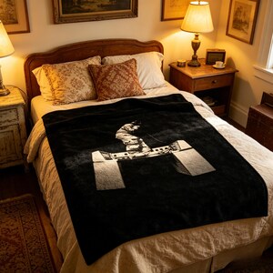 May include: A black blanket with a white graphic of a person snowboarding. The blanket is on a bed with patterned pillows and a wooden headboard. The room has lamps and antique furniture.