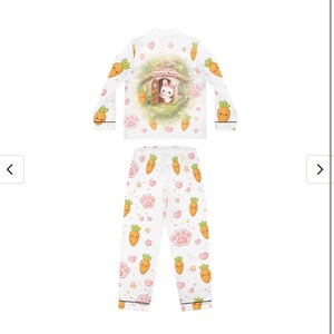 Pu&ograve; includere: Set pigiama bianco con top a maniche lunghe e pantaloni. Il top presenta una grafica di un coniglietto in una casa con la scritta "Sweetest Bunny". Il set &egrave; decorato con carote dei cartoni animati, impronte di zampe e cuori.