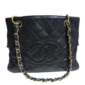 May include: Black quilted leather handbag with gold-tone chain straps. The bag features a diamond pattern and a prominent double-C logo on the front. The bag has a textured finish and a rectangular shape.