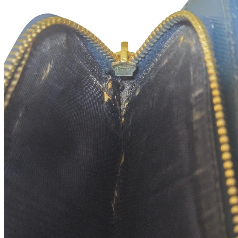 May include: Close-up of an open blue wallet with a gold zipper. The interior is black, and the zipper is partially open, revealing the inside of the wallet. The zipper is a bright gold color.