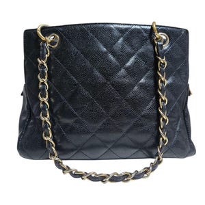May include: Black quilted leather tote bag with gold-tone chain straps. The bag features a diamond pattern and a textured surface. The chain straps are interwoven with black leather.