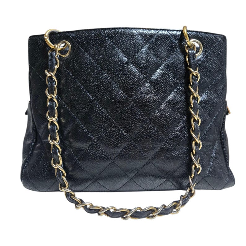 May include: Black quilted leather tote bag with gold-tone chain straps. The bag features a diamond pattern and a textured surface. The chain straps are interwoven with black leather.