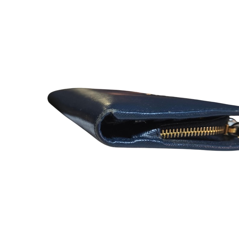 May include: A navy blue leather wallet with a gold zipper. The wallet is closed and the zipper is visible along the edge. The leather has a slight sheen.