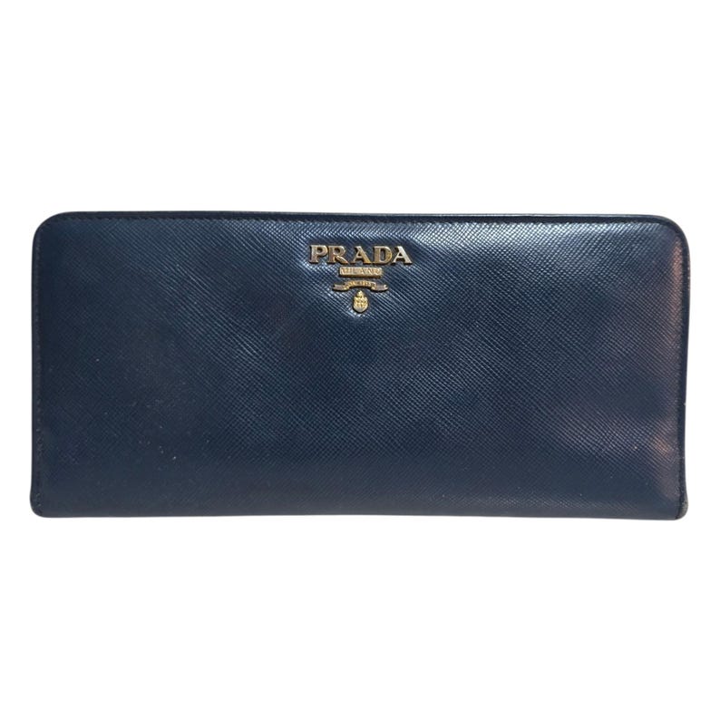 May include: A navy blue leather wallet with the gold-colored brand name "PRADA" embossed on the front. The wallet has a rectangular shape and a smooth texture. The Prada logo is centered above the wallet's midpoint.