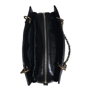 May include: Black leather tote bag with a gold-tone zipper and chain strap. The bag has a textured finish and a structured shape. The interior is black and appears to have multiple compartments. The bag has gold-tone hardware.