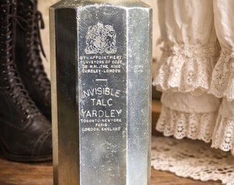 May include: An antique, silver-colored Yardley Invisible Talc container. The octagonal bottle has a tarnished metal finish and a bronze-colored cap. Text on the bottle includes "Yardley" and "London, England."
