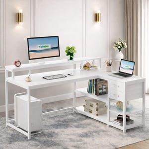May include: White L-shaped computer desk with a monitor, keyboard, and laptop. The desk has multiple shelves for storage and a built-in drawer unit. The desk is in a home office setting with a rug and wall decor.