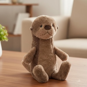 Op de afbeelding: Een bruin pluche otter speelgoed met een zachte, getextureerde uitstraling. De otter heeft een ronde kop, kleine oren en een donkerbruine neus. Hij zit rechtop met zijn armen en benen uitgestrekt.