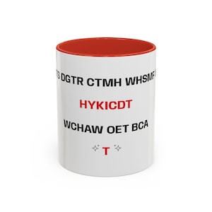 Könnte beinhalten: Weißer Keramikbecher mit roter Innenseite. Der Becher hat den Text "HYKICDT" in Rot, umgeben von anderem Text und zwei Sternsymbolen mit dem Buchstaben "T" in der Mitte. Geeignet für Heißgetränke.