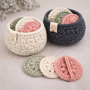 May include: Two small, round, crocheted baskets, one cream and one dark gray, each filled with matching crocheted pads in shades of green, cream, and pink. The baskets have a textured pattern and a small tag that reads "Love Vieamile".