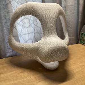 May include: A white 3D printed animal mask base featuring a rounded snout, large eye openings, and a textured surface. The structure is hollow and lightweight, designed with a curved top and a protruding muzzle area, showing visible layer lines.