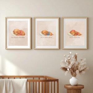 May include: Three framed wall art prints featuring illustrations of sleeping golden puppies on white pillows. Each print includes text in a light brown font: 'Jeg slipper deg ikke', 'Du er aldri alene', and 'Jeg er med deg' on a soft beige background.