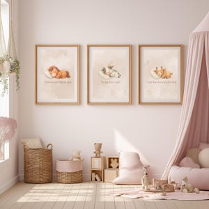 May include: Three framed wall art prints featuring watercolor illustrations of a sleeping horse, cow, and goat on pillows. Each print includes text in a light beige tone with wooden frames, displayed in a nursery setting with soft pink decor.