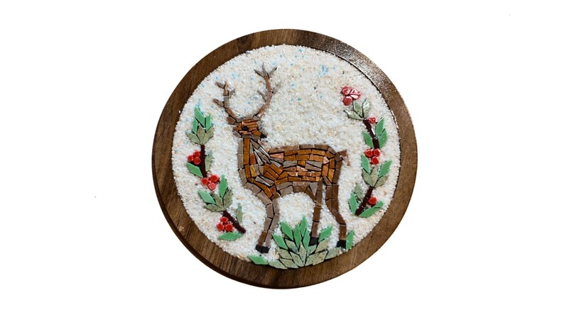 May include: Round wooden mosaic featuring a deer with antlers, crafted from brown and tan tiles. The deer is surrounded by green leaves and red berries on a white background, set within a dark brown wooden frame.