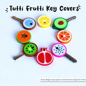 May include: A collection of key covers with fruit designs, including a lemon, kiwi, and orange. The key covers are colorful and round, with the text "Tutti Frutti Key Covers" at the top. Some designs may require a small amount of glue for final assembly.