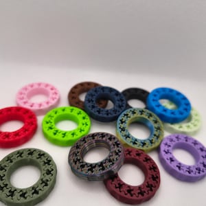 May include: A collection of colorful, circular objects with a star-shaped pattern. The objects are in various colors, including red, pink, green, blue, and purple. The objects are arranged on a white surface.