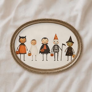 以下が含まれることがあります： 楕円形の額縁に入ったウォールアートで、ハロウィンの仮装をした5人のキャラクター（猫、幽霊、吸血鬼、鎌を持った骸骨、魔女）の水彩画が描かれています。それぞれのキャラクターは、小さなオレンジ色のカボチャのバケツを持っています。