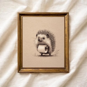 May include: A framed pencil sketch of a hedgehog holding a roll of toilet paper. The artwork is in a gold-colored frame and set against a neutral background. The hedgehog is depicted with detailed shading, giving it a realistic appearance.