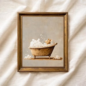 May include: A framed wall art print featuring a light brown mouse sitting inside a vintage-style clawfoot bathtub filled with white soap bubbles. The artwork is encased in a metallic gold frame, set against a neutral, textured background.
