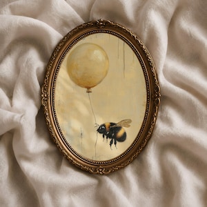 May include: An oval-shaped wall art piece featuring a painting of a fuzzy bumblebee holding a string attached to a pale yellow balloon. The artwork is encased in an ornate, antique-style gold frame with intricate decorative detailing.