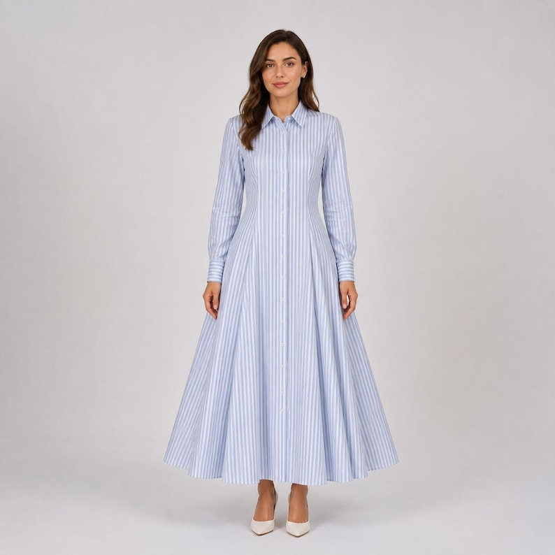 May include: A floor-length shirt dress featuring a light blue and white vertical striped pattern. The garment has a classic collar, long sleeves with buttoned cuffs, a button-down front placket, and a fitted waist that flares into a full skirt.