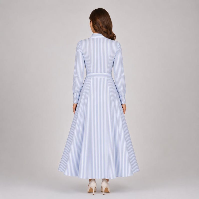 May include: A long-sleeved, floor-length dress featuring a light blue and white vertical striped pattern. The garment has a collared neckline, a fitted bodice with a defined waistline, and a full, flared skirt that extends to the floor.