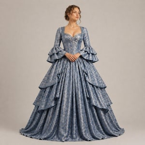 K&ouml;nnte beinhalten: Ein blau-silbernes Ballkleid mit Muster, langen &Auml;rmeln und ger&uuml;schten Manschetten. Das Kleid hat einen herzf&ouml;rmigen Ausschnitt und einen mehrschichtigen Rock. Das Kleid ist bodenlang und hat ein eng anliegendes Oberteil.