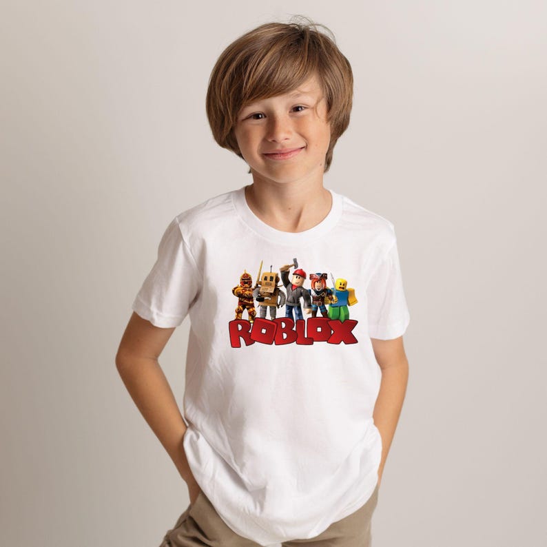 a young boy standing in front of a couch wearing a roblox shirt