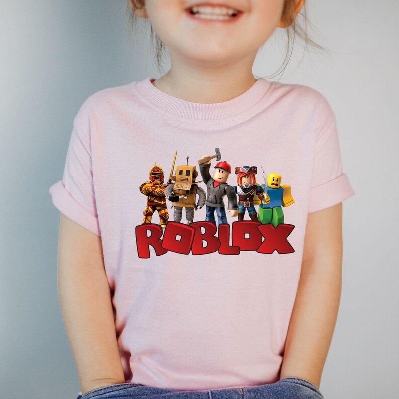 a young girl standing in front of a couch wearing a roblox shirt