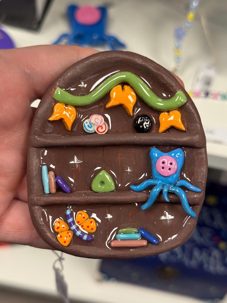 Unique clay mini bookshelf inspired by Coraline’s bedroom and themes. Made with oven bake clay and cured with resin for shine & protection.