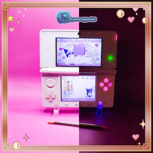 May include: A white handheld gaming console featuring dual screens, a directional pad, and action buttons. The top screen displays a Kuromi character graphic, while the bottom screen shows a menu interface. A metal stylus rests below the console.