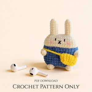 May include: A crocheted bunny-shaped AirPod case in white, blue, and yellow, with a small yellow bag. Two white AirPods are visible. The text "PDF DOWNLOAD CROCHET PATTERN ONLY" is at the bottom. The case is a cute accessory.