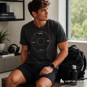 May include: Dark gray t-shirt with a white graphic of a circular music player interface, including a menu button, play/pause, and skip buttons. The shirt is paired with black shorts. A black backpack and water bottle are also visible.