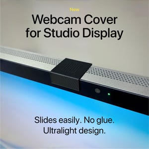 May include: A black webcam cover for a Studio Display. The cover slides easily and has an ultralight design. The text "Webcam Cover for Studio Display" is visible, along with "Slides easily. No glue. Ultralight design."