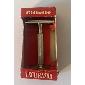 May include: A vintage Gillette Tech Razor in its original red and white box. The razor has a silver handle with a textured grip. The box reads "Gillette" at the top and "TECH RAZOR" at the bottom.