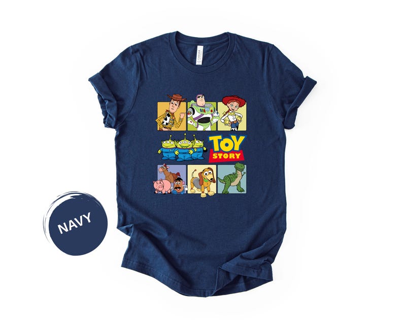 May include: A navy blue short-sleeve t-shirt featuring a graphic print of Toy Story characters including Woody, Buzz Lightyear, Jessie, the Aliens, Bullseye, Hamm, Mr. Potato Head, Slinky Dog, and Rex, with the text Toy Story in yellow and red.
