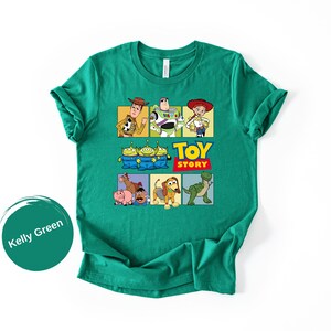 May include: A kelly green short-sleeve t-shirt featuring a graphic print of Toy Story characters including Woody, Buzz Lightyear, Jessie, the Aliens, Bullseye, Hamm, Mr. Potato Head, Slinky Dog, and Rex, with the Toy Story logo text.