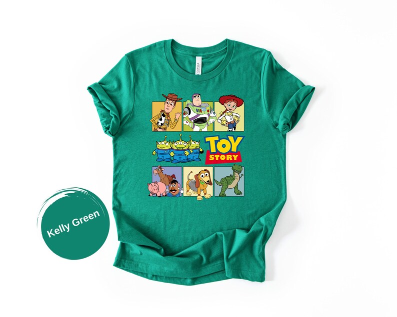 May include: A kelly green short-sleeve t-shirt featuring a graphic print of Toy Story characters including Woody, Buzz Lightyear, Jessie, the Aliens, Bullseye, Hamm, Mr. Potato Head, Slinky Dog, and Rex, with the Toy Story logo text.